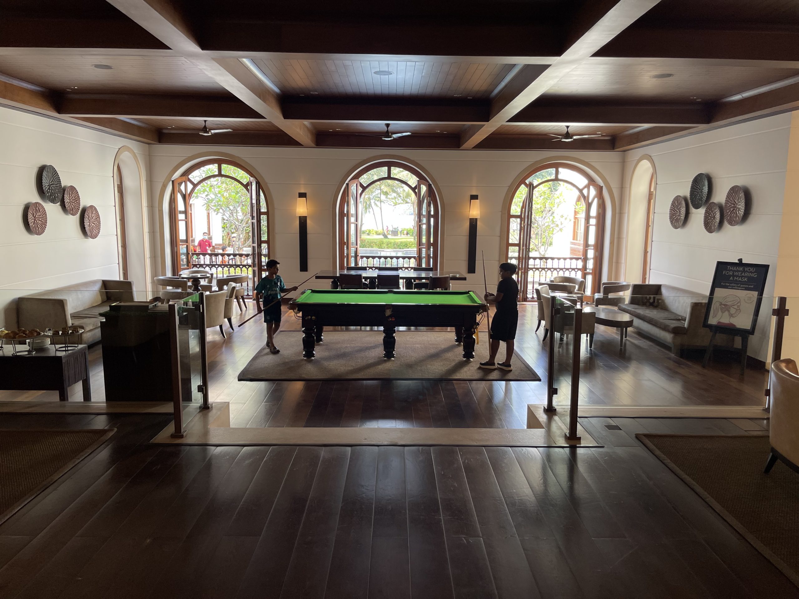 a pool table in a room with a couple people standing around