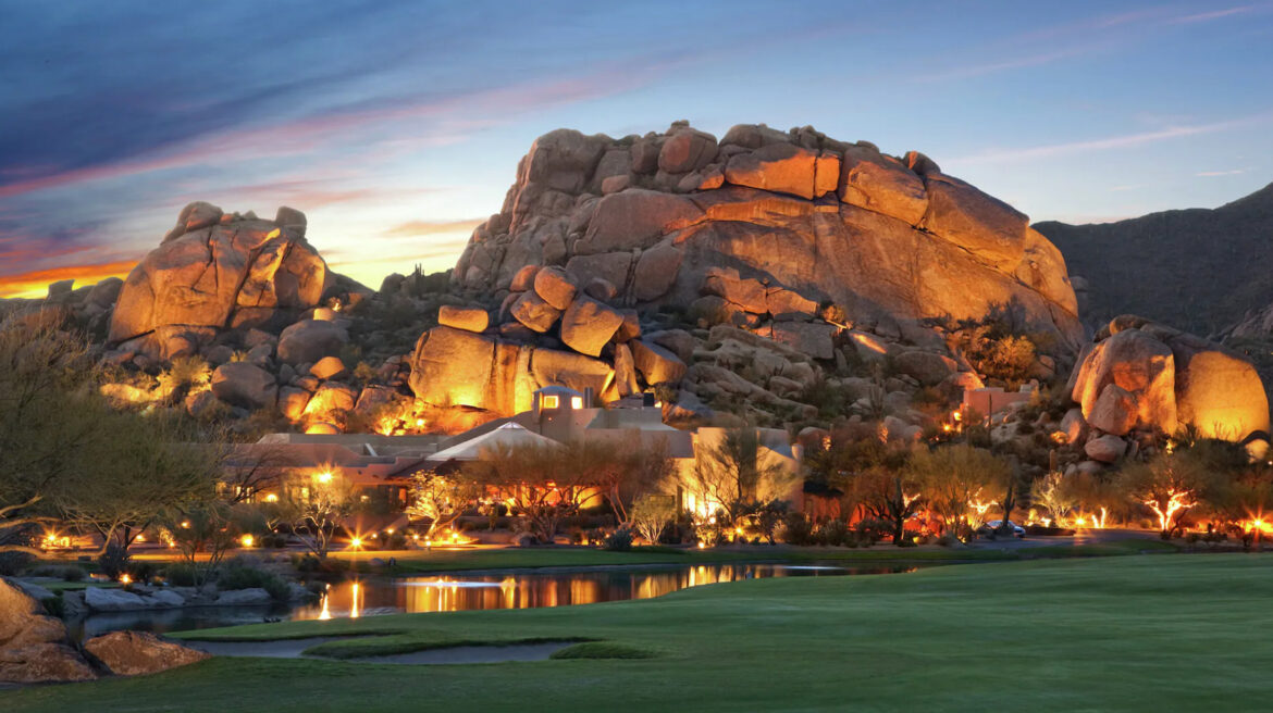 a large rock formation with a house and a lake