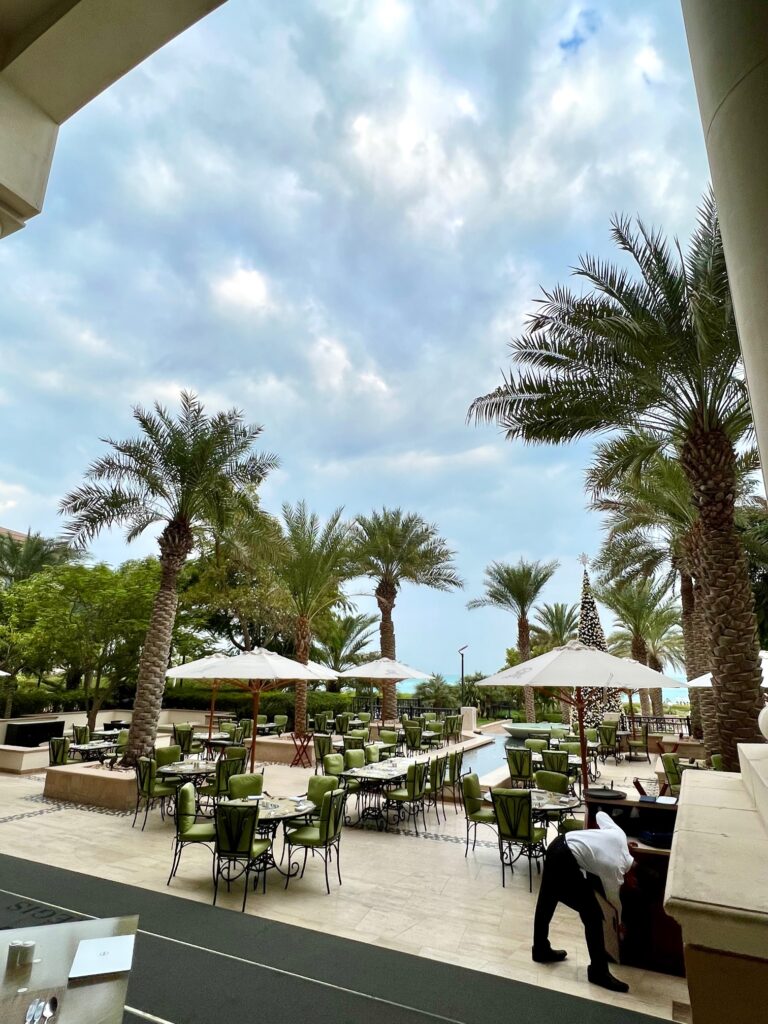 a patio with tables and umbrellas and palm trees