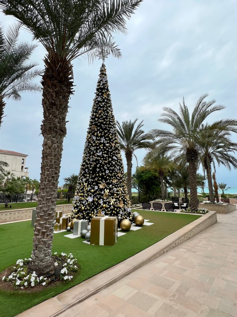 a large christmas tree with presents and a palm tree in the background