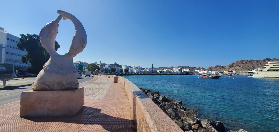 a stone statue on a sidewalk next to a body of water