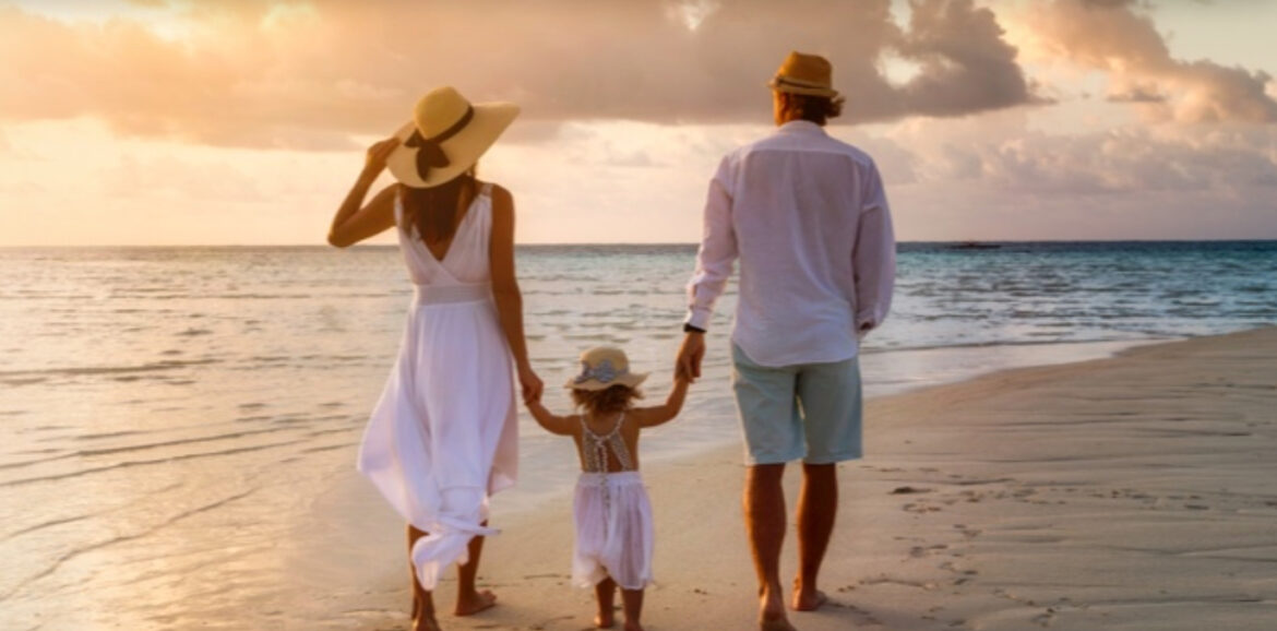 a man and woman holding hands and walking on a beach