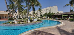 Hilton Honors Status Match Program a pool with palm trees and buildings in the background