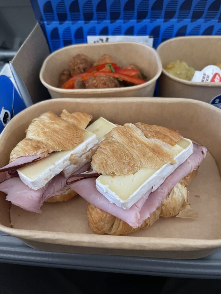 a croissant sandwich with ham and cheese in a basket