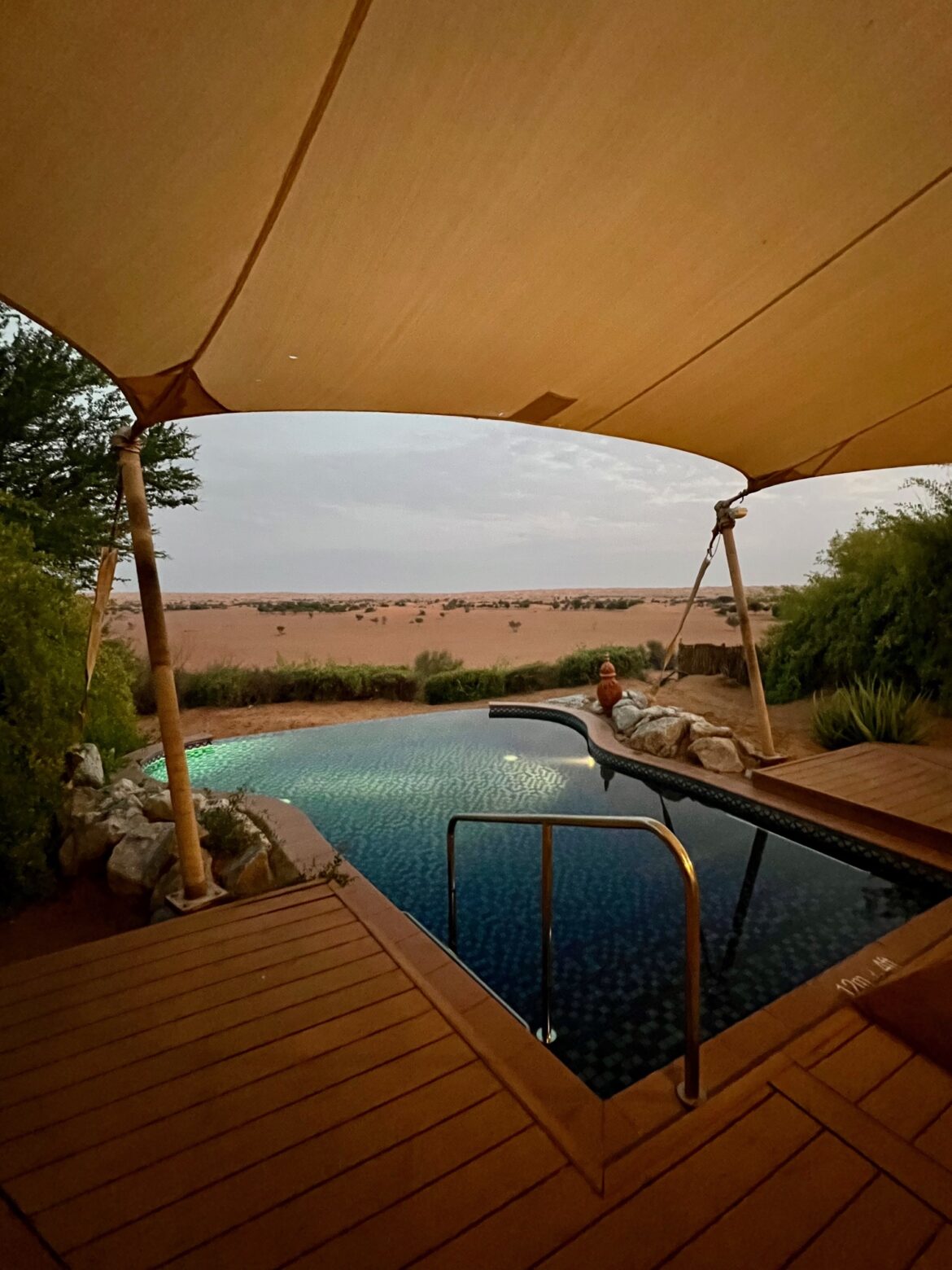 a pool with a wooden deck and a wooden deck with a large sand dune