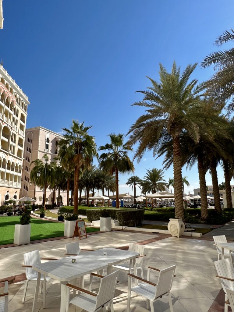 a group of white tables and chairs in a courtyard with palm trees