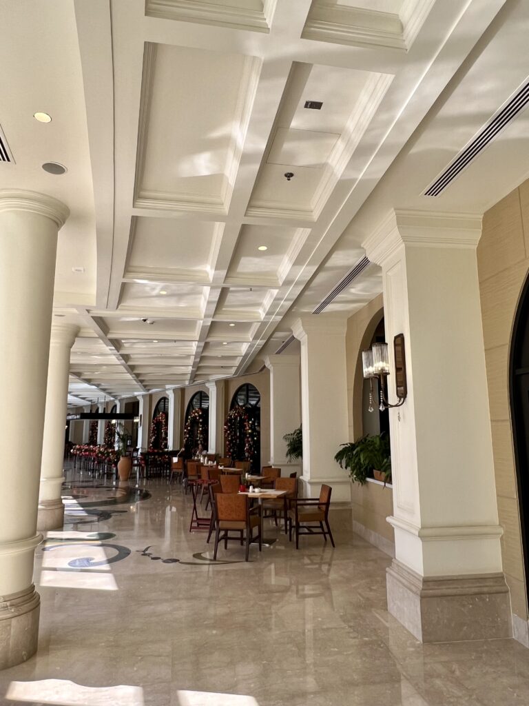 a long hallway with white columns and tables and chairs