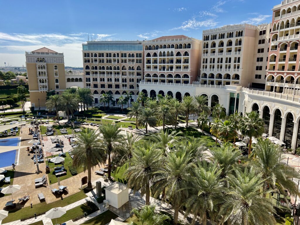 a large building with many windows and a courtyard with palm trees