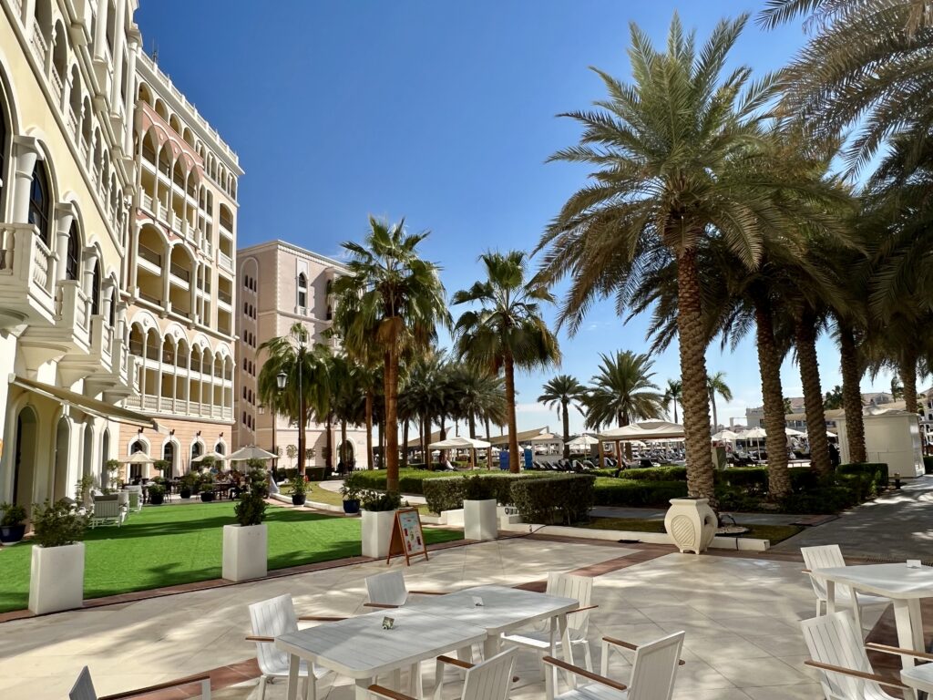 a white tables and chairs in a courtyard with palm trees