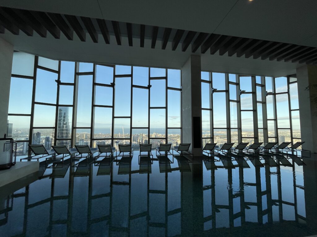 a large indoor pool with chairs and a view of a city