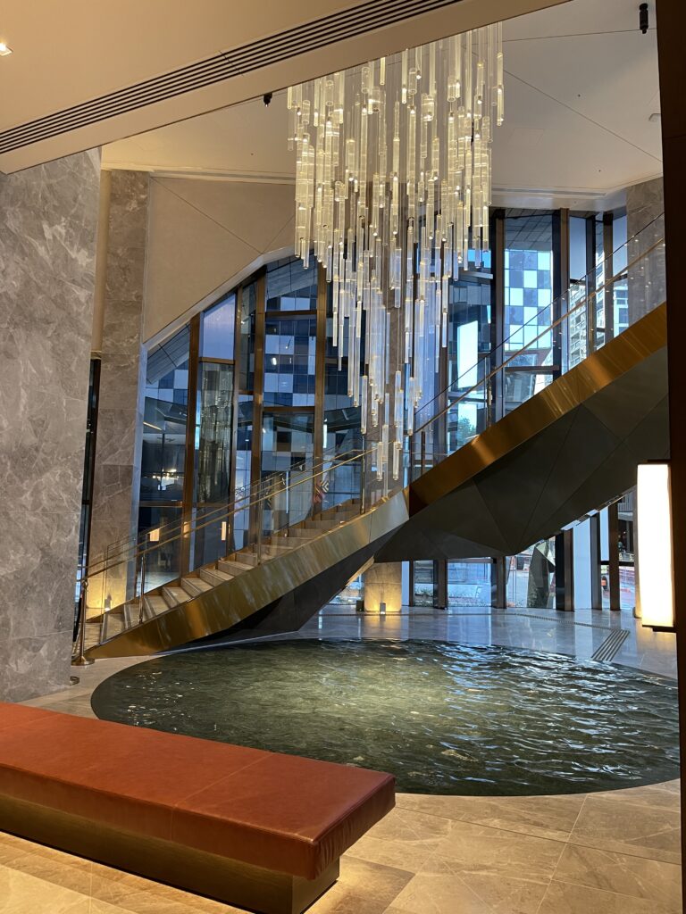 a staircase with a large chandelier and a pool in a building
