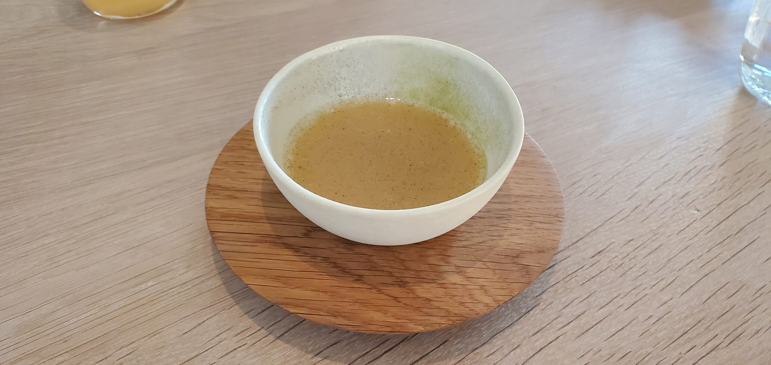 a bowl of brown liquid on a wood plate