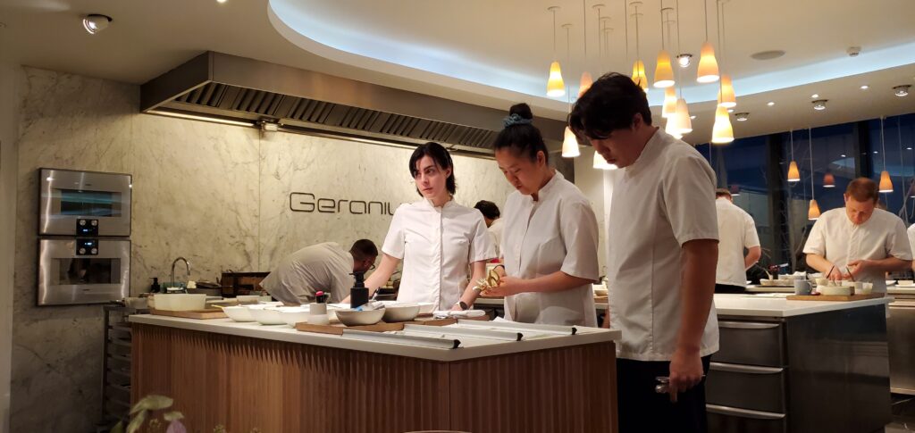 a group of people in white uniforms standing in a kitchen