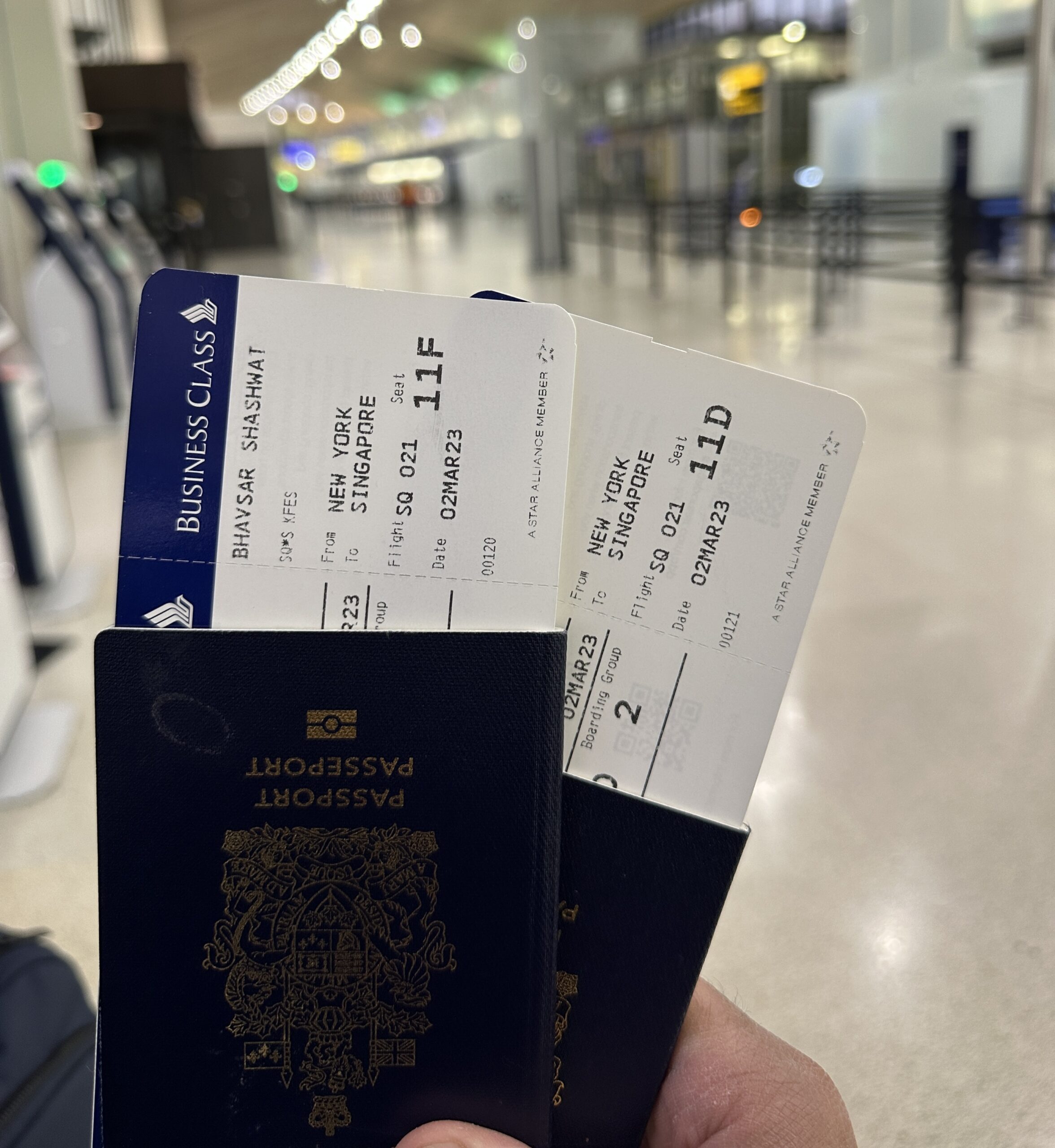 a hand holding two passports with boarding pass tickets