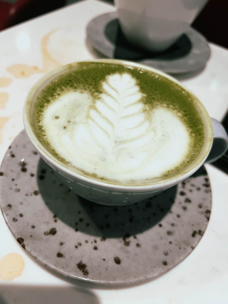a cup of green tea with a leaf design in the foam