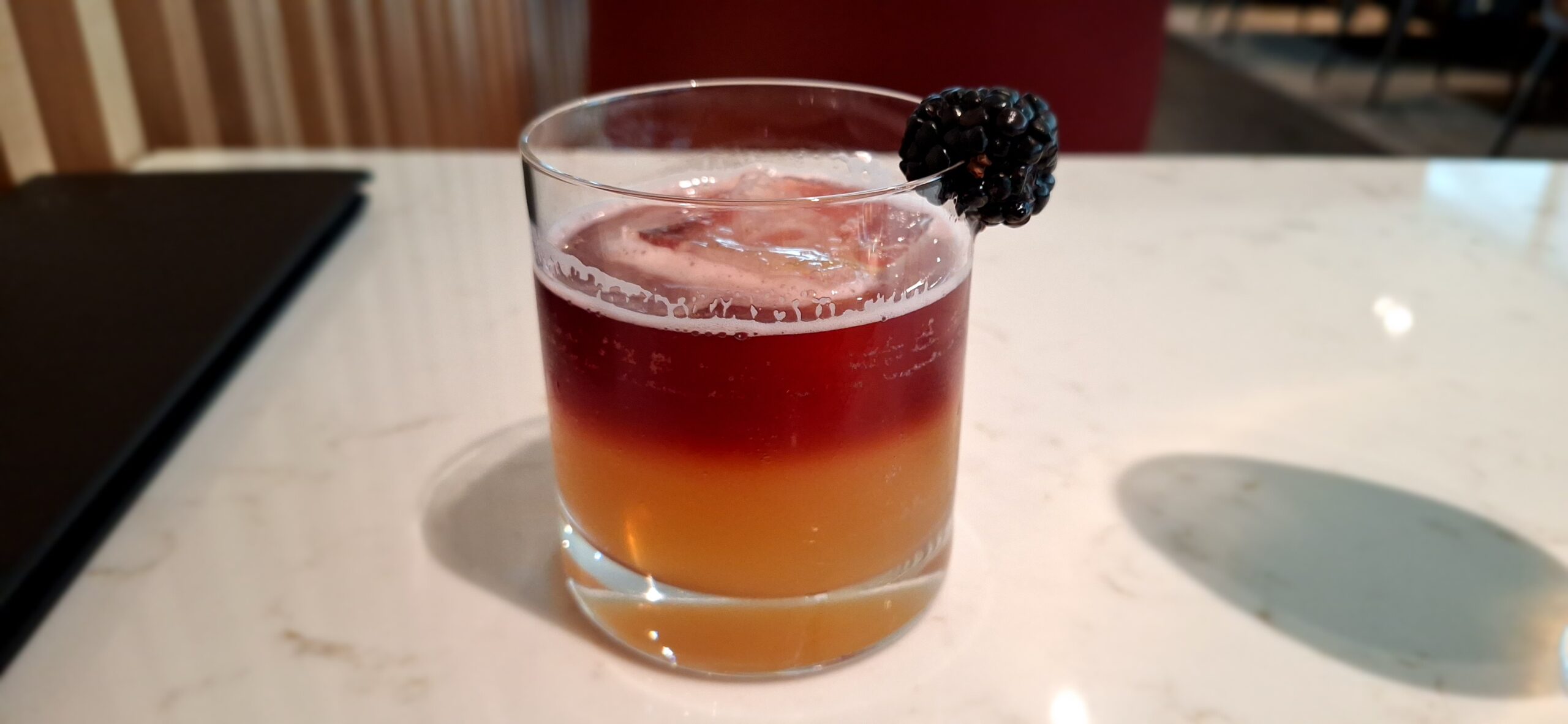 a glass with a drink and a black berry on top