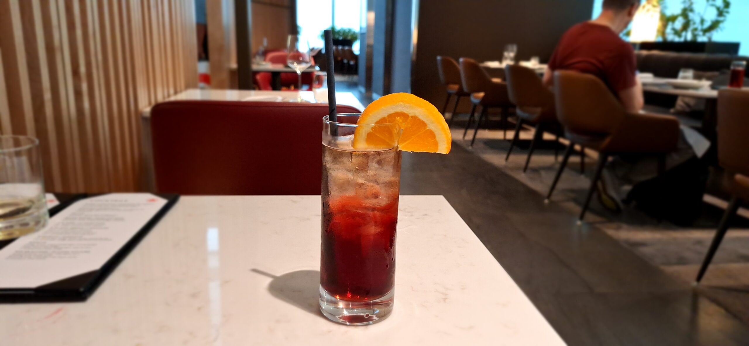 a glass of red liquid with a slice of orange on top of it