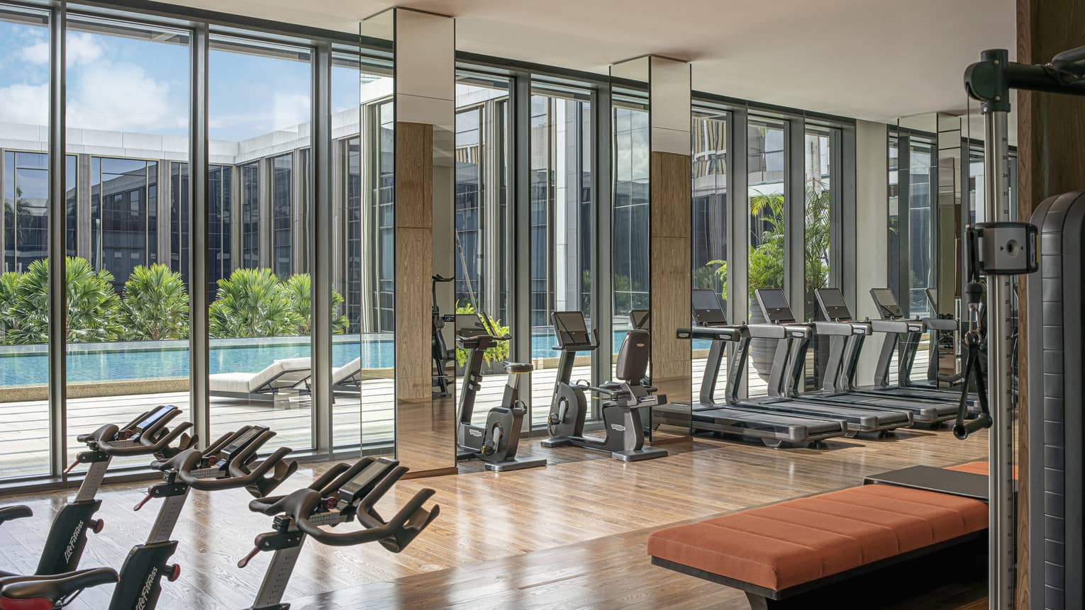 a room with exercise equipment and a pool in the background