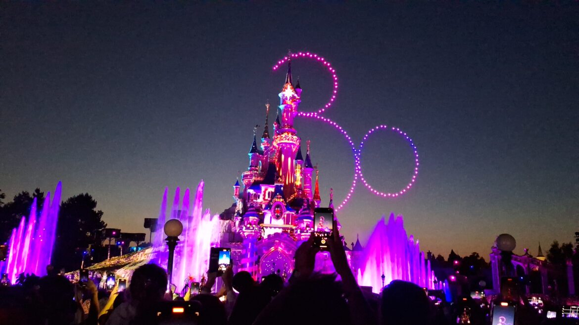 a castle with lights and a fountain in front of it