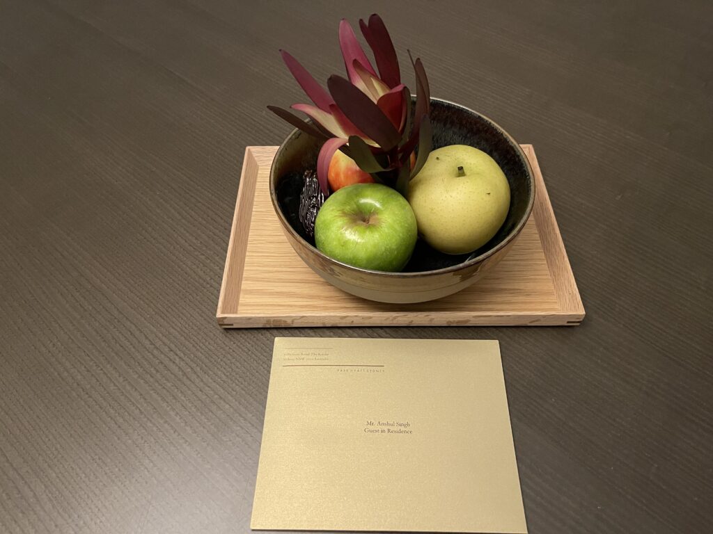 a bowl of fruit on a wood tray next to a card