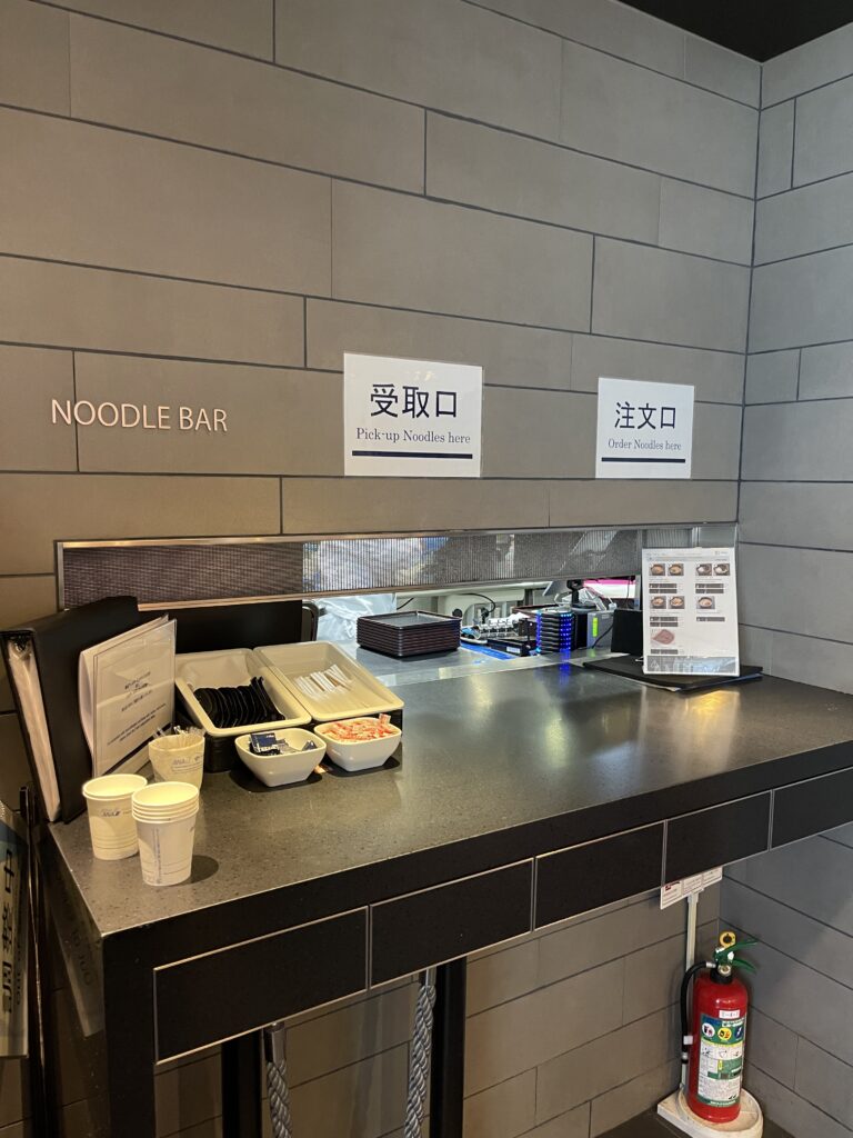 a counter with noodle bar signs