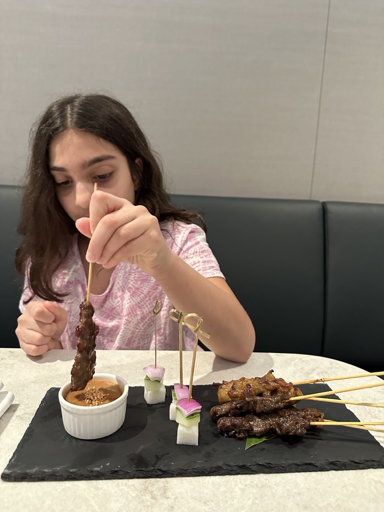 a girl eating meat on skewers