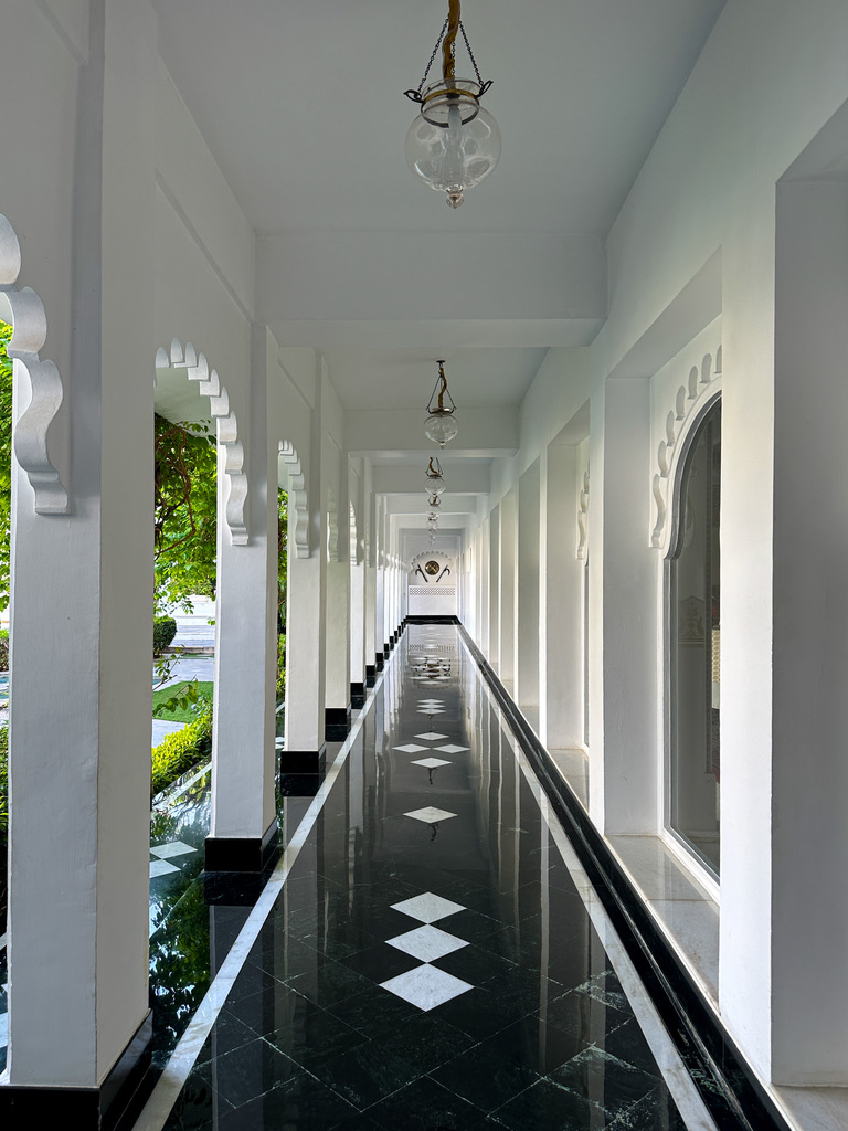 a long black and white hallway with white pillars and a black and white floor