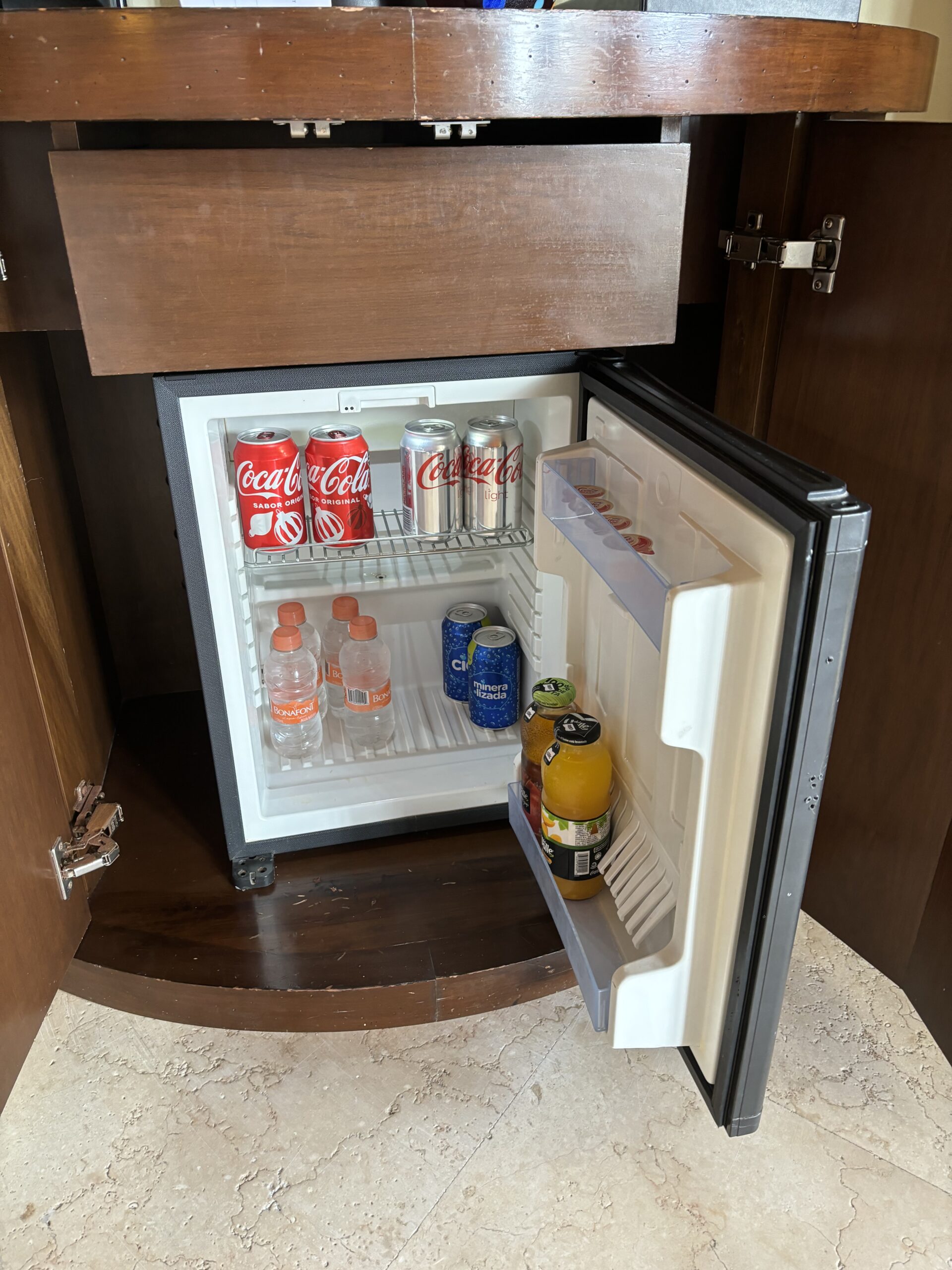 a mini fridge with soda cans and bottles inside