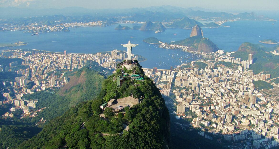 a statue on a mountain with a city in the background