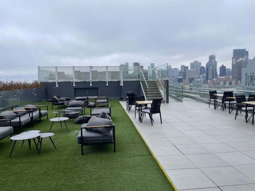 a rooftop patio with chairs and tables and a city skyline