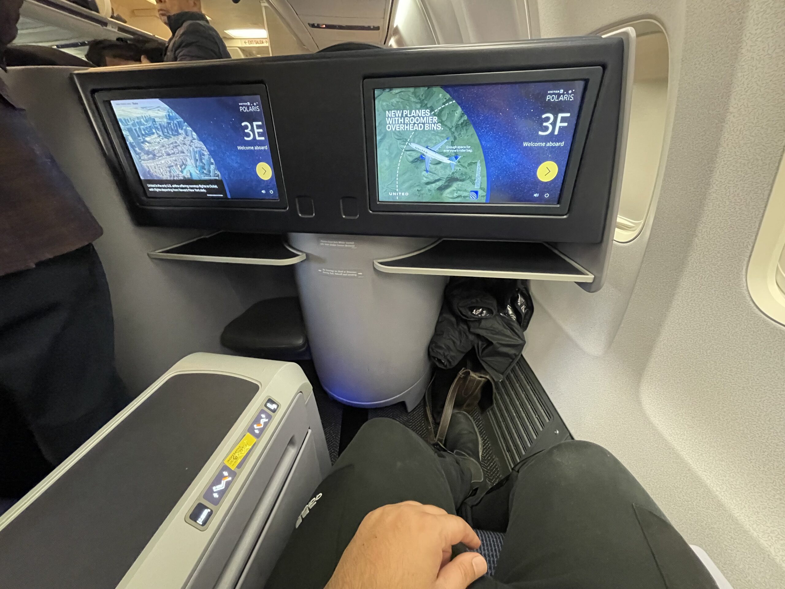 a person's legs in a seat with a screen on the side of the seat