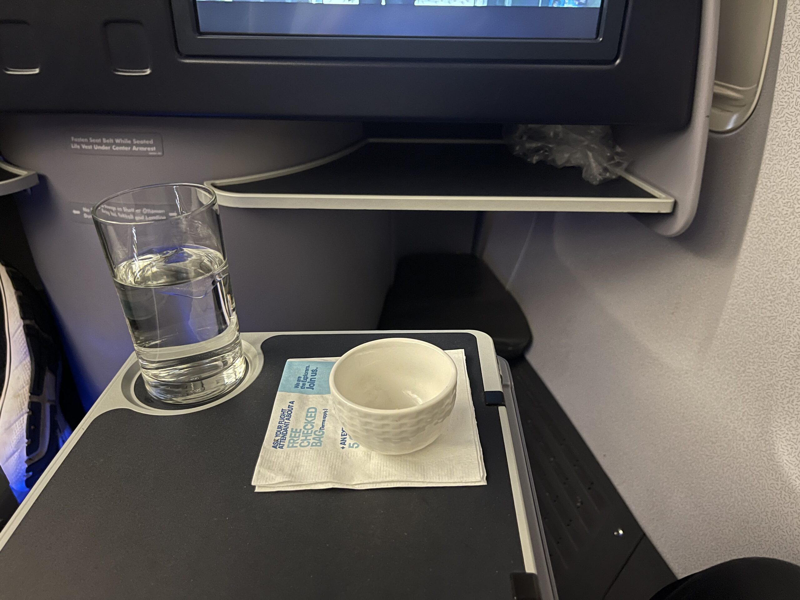 a glass of water and a bowl on a tray in an airplane