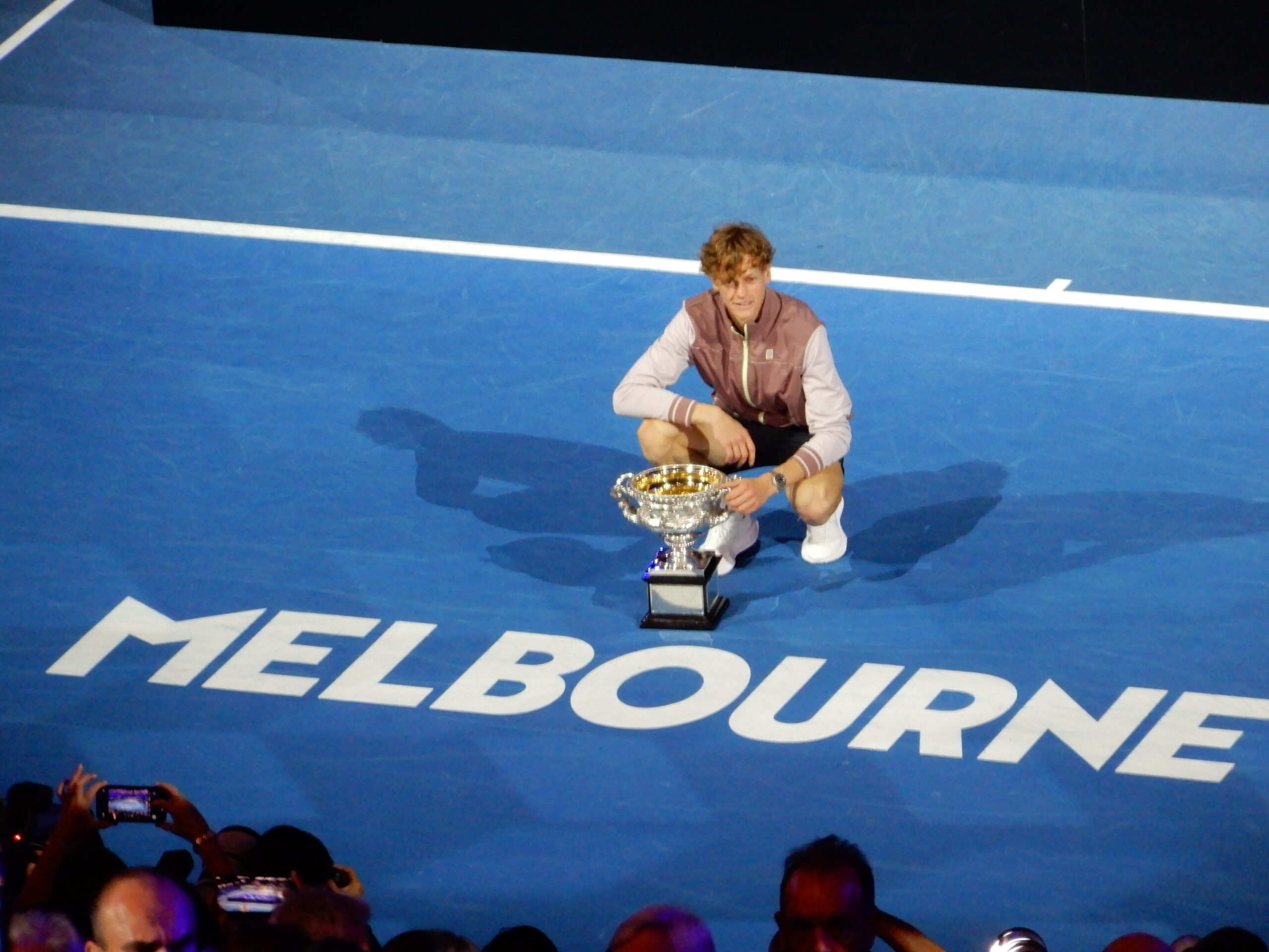 a man kneeling on a blue surface with a trophy