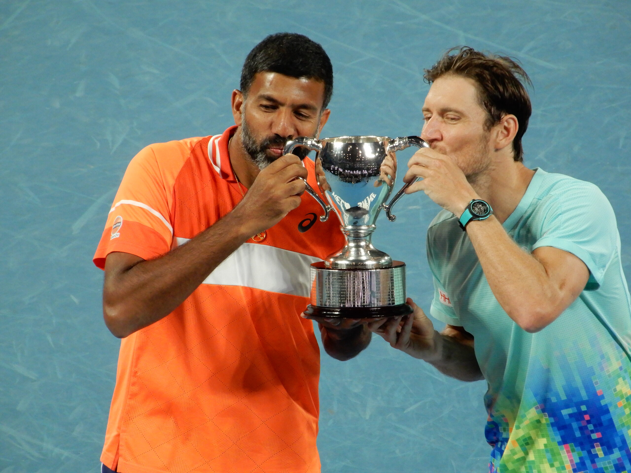 two men kissing a trophy