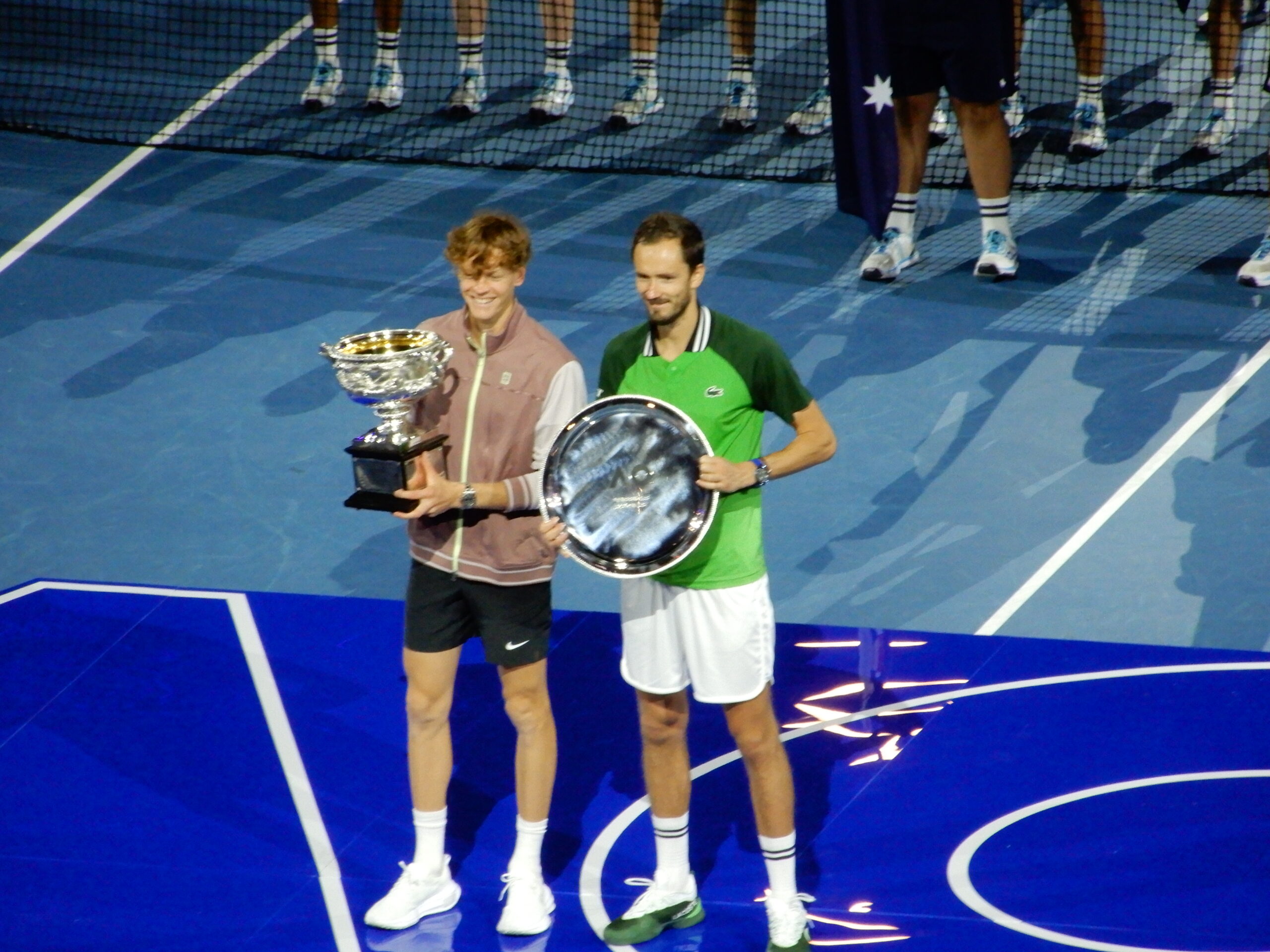 two men holding a trophy on a tennis court