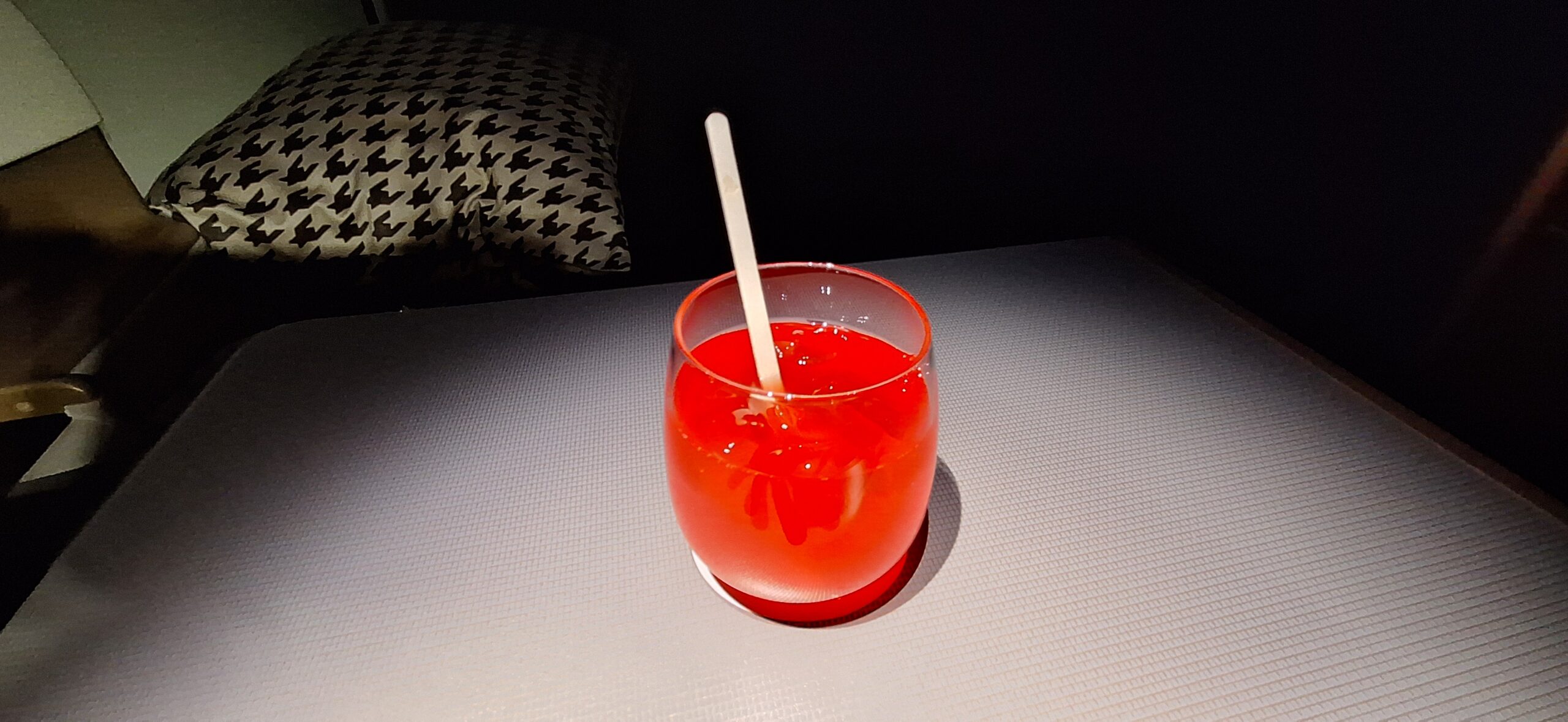 a glass with red liquid and a wooden spoon