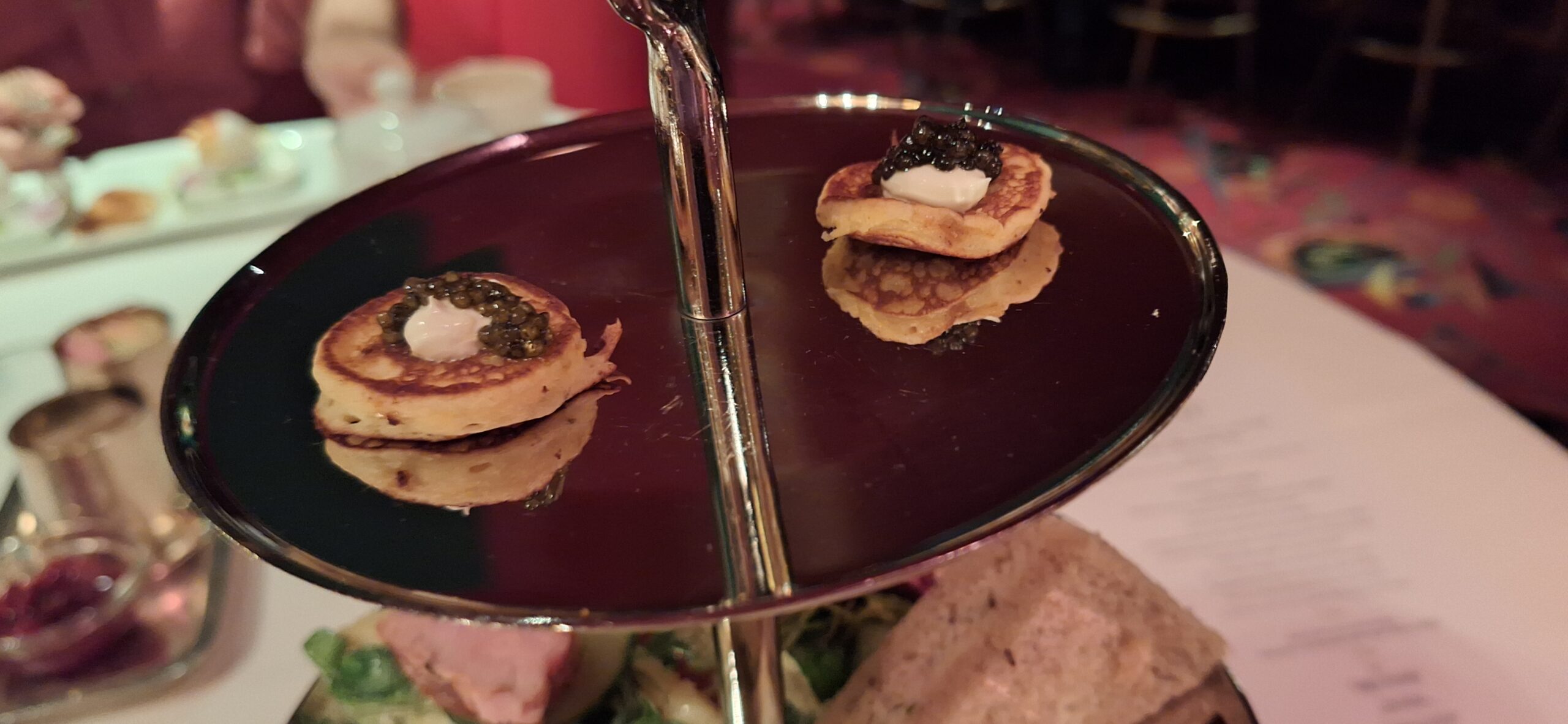 a group of small pancakes with black caviar on a glass tray
