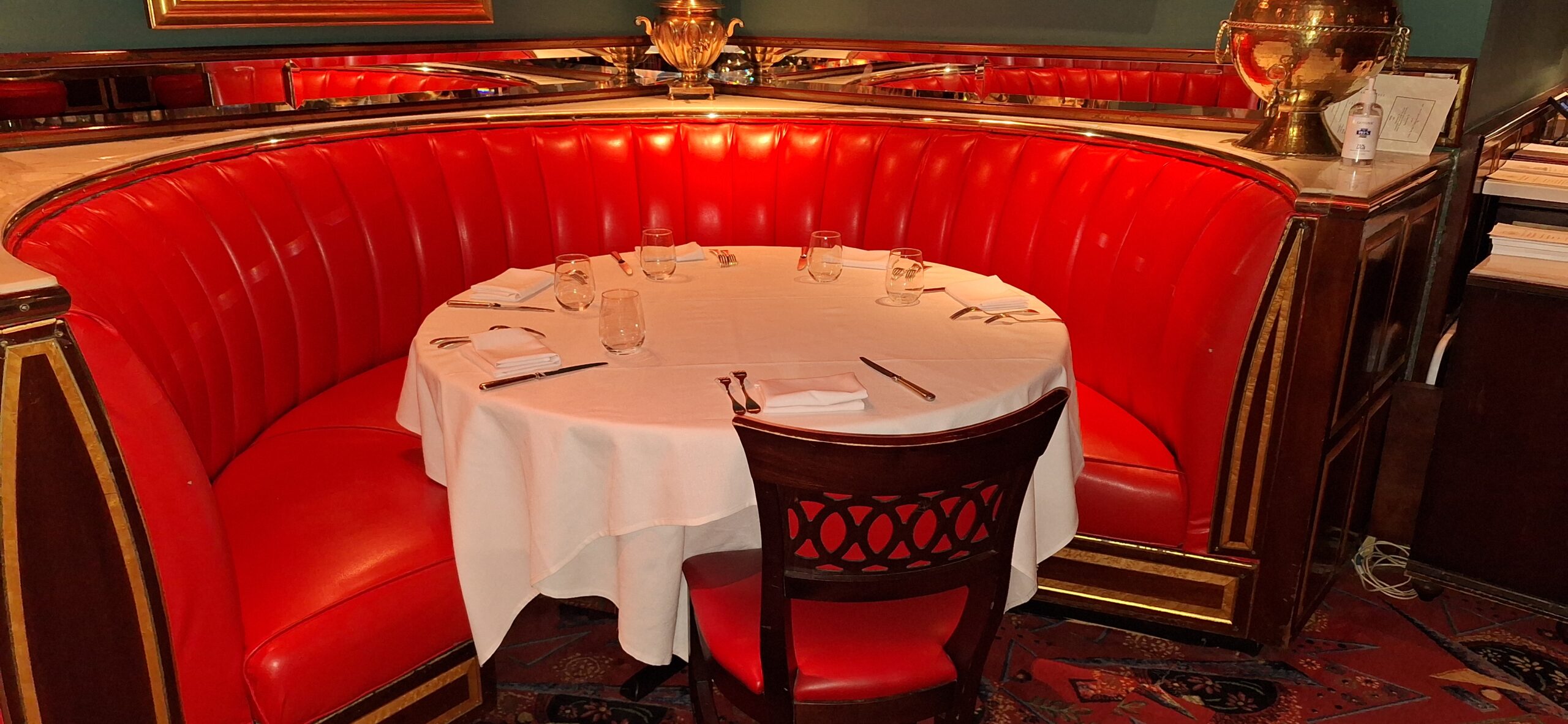 a table with a white tablecloth and red booth seating