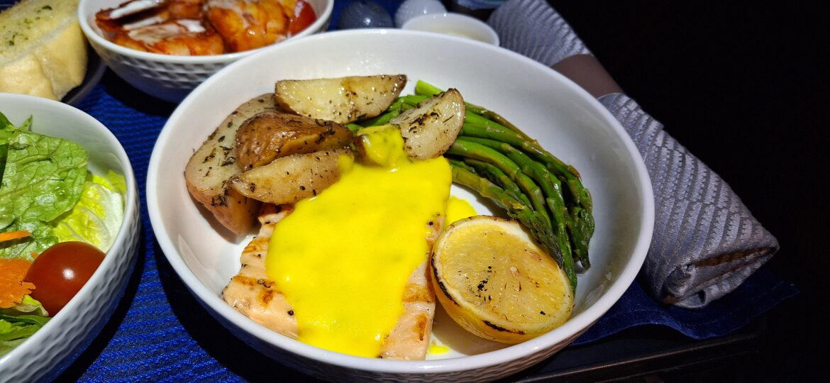United Flight – grilled salmon a plate of food with lemon and asparagus