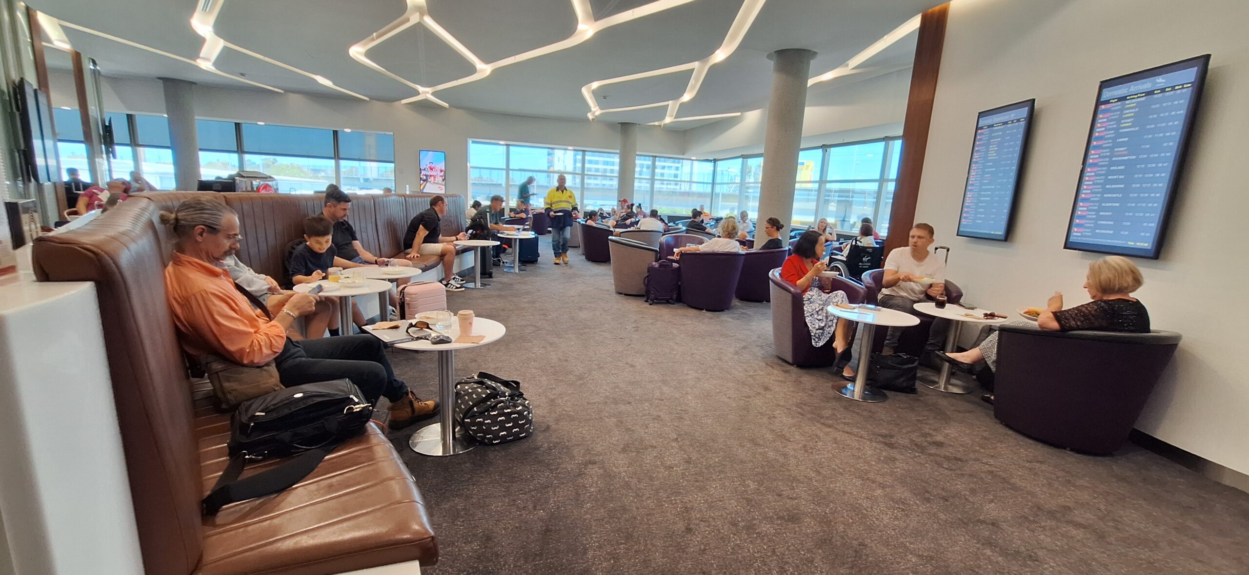 a group of people sitting at tables in a room with large windows