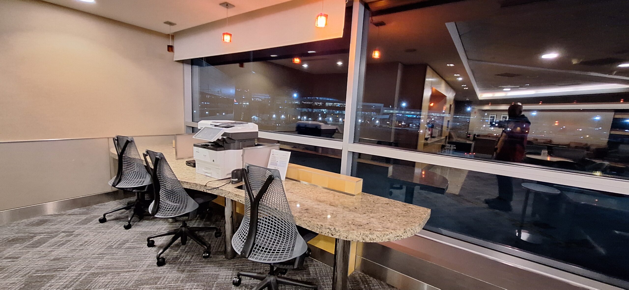 a desk with chairs and a printer in front of a window