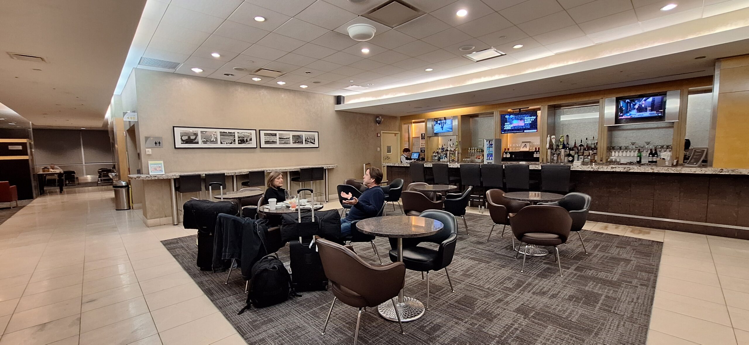 people sitting at tables in a room with chairs and luggage