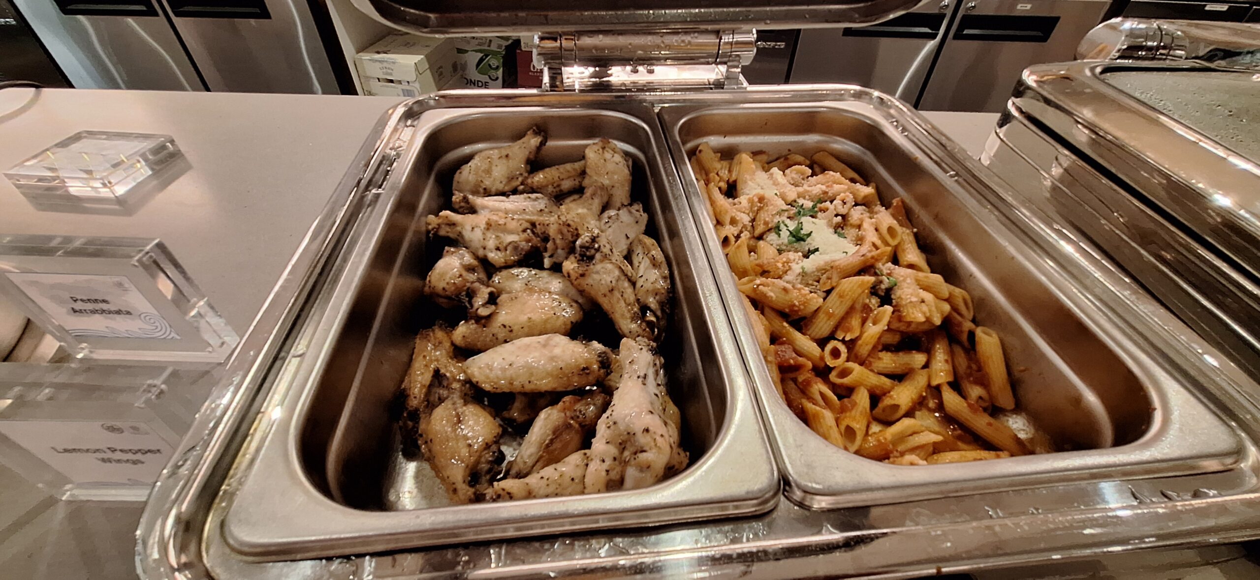 a tray of food with chicken wings and pasta