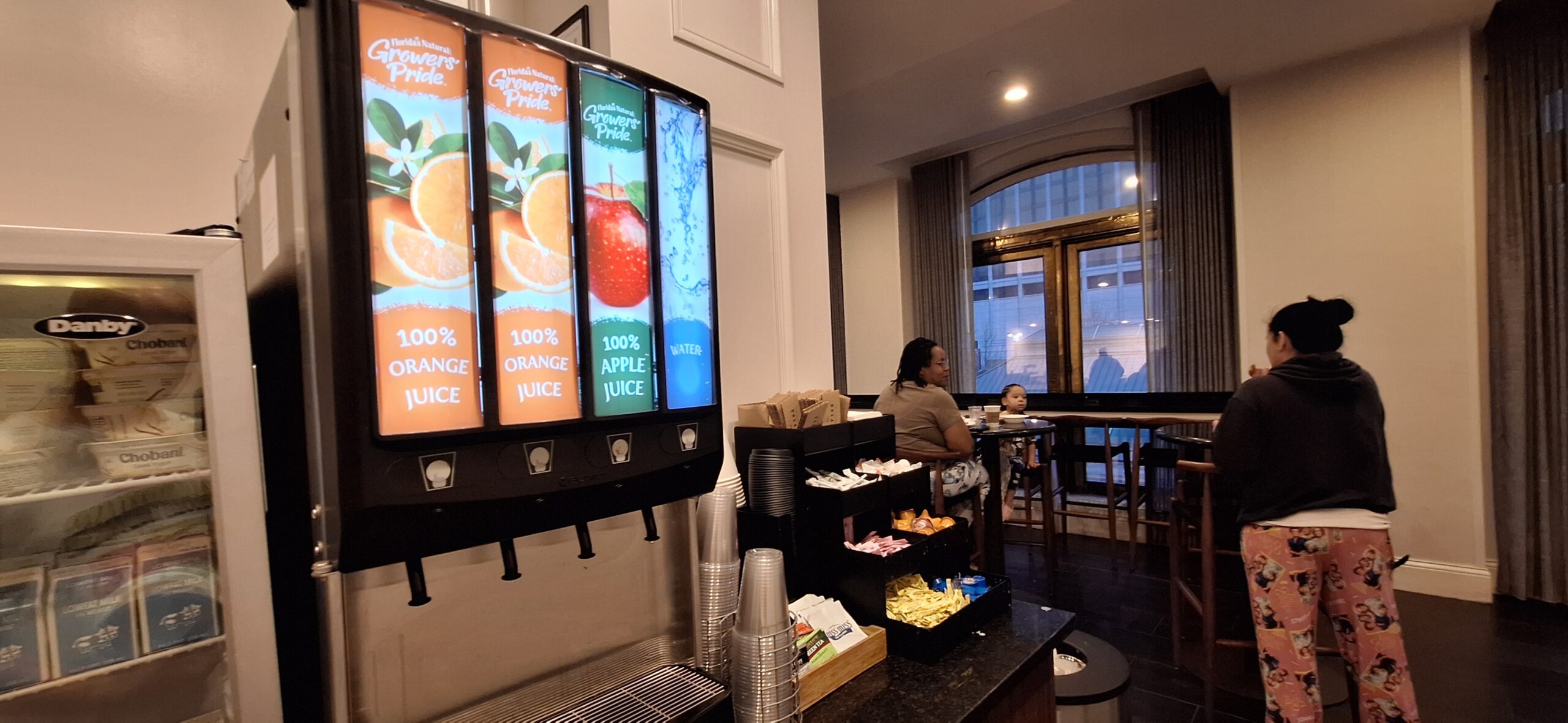 a woman sitting at a table with a drink dispenser