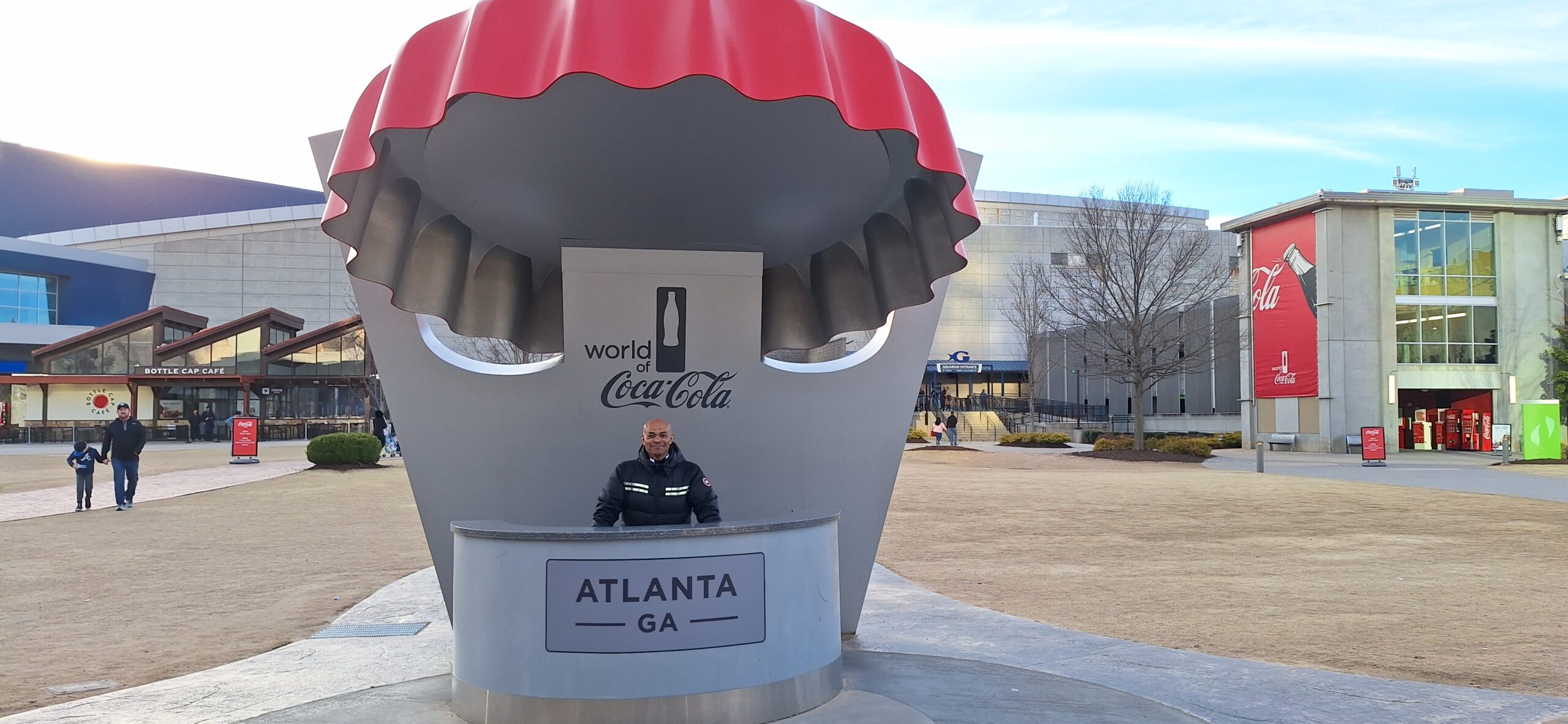 a man standing at a counter in front of a large red and white sign