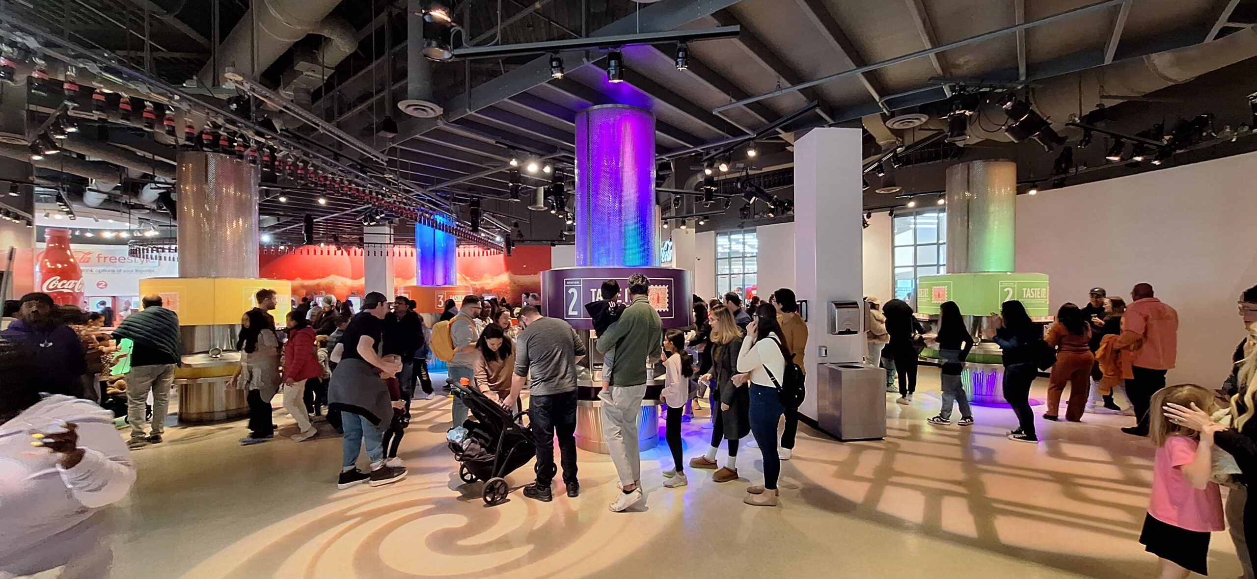 a group of people in a room with a large column and a purple light