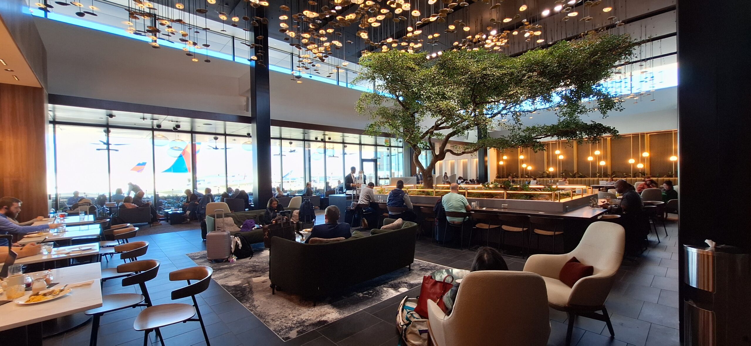 a group of people sitting in a room with a tree and lights