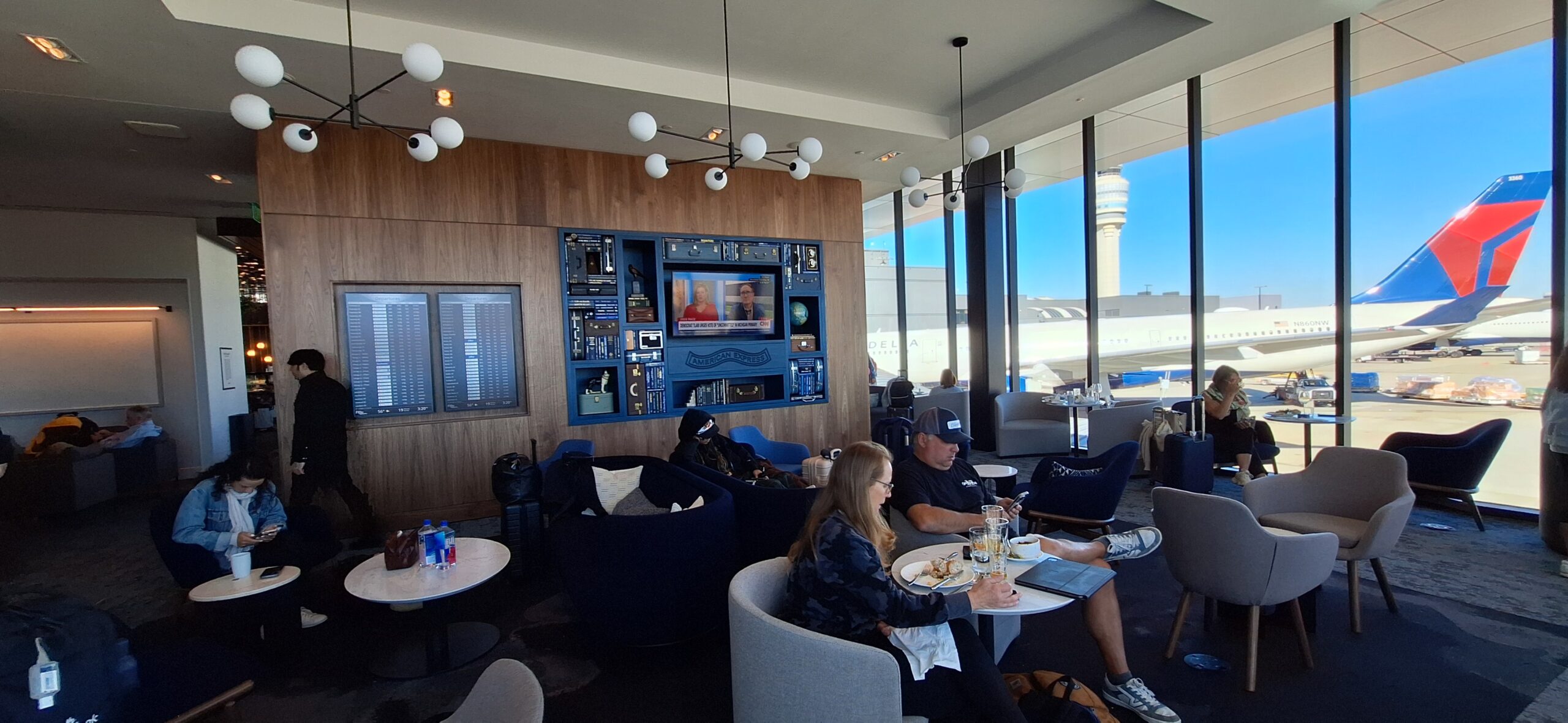 people sitting at tables in a room with a television screen