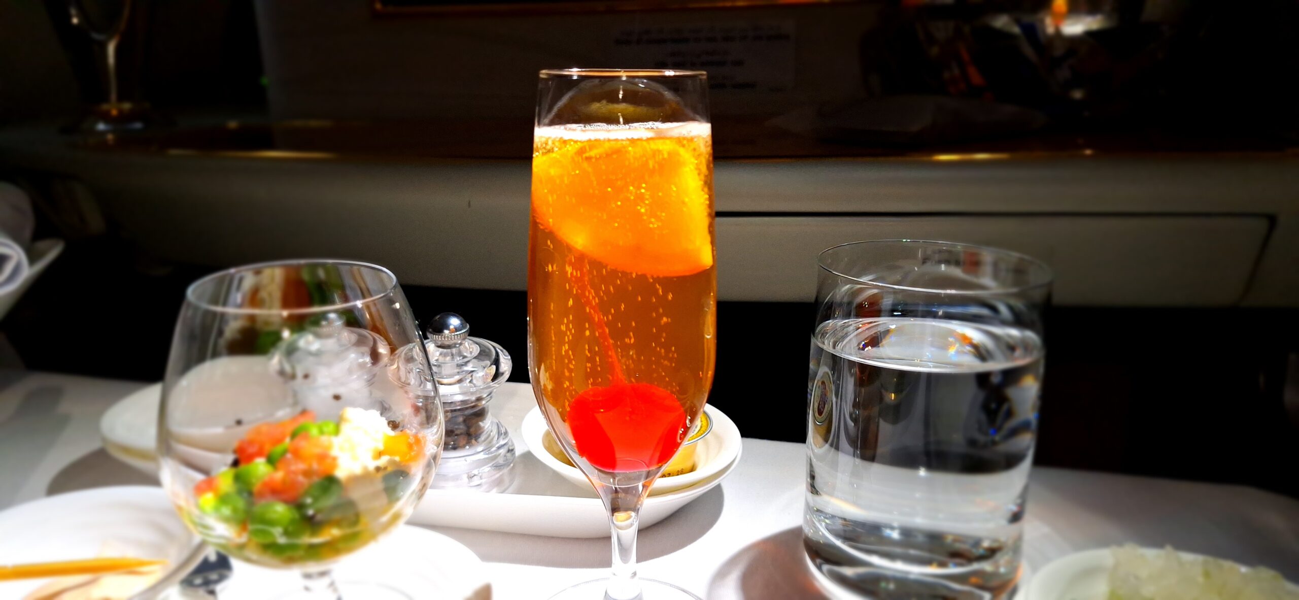 a glass of orange liquid with a cherry in it