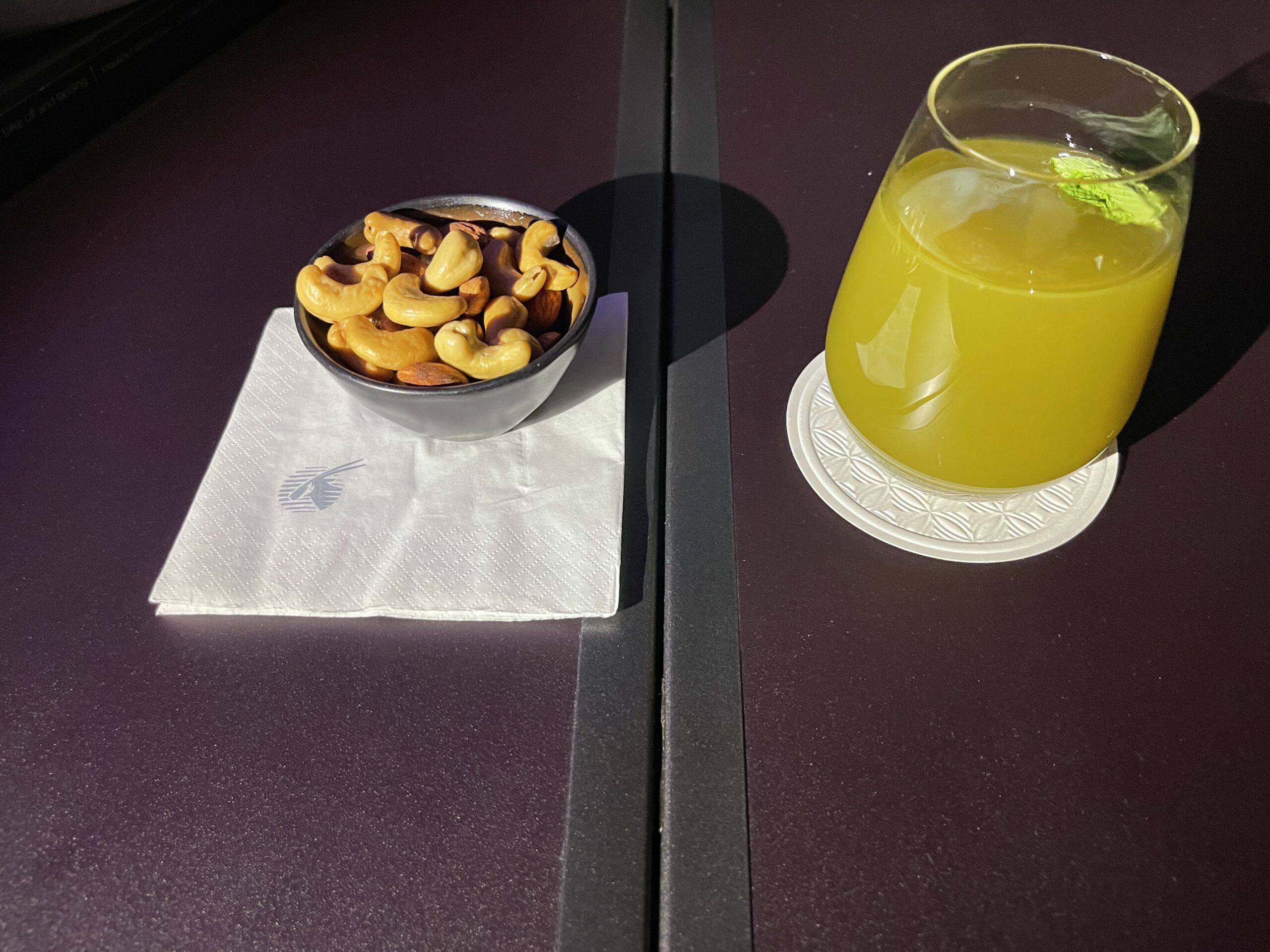 a bowl of cashews and a glass of juice